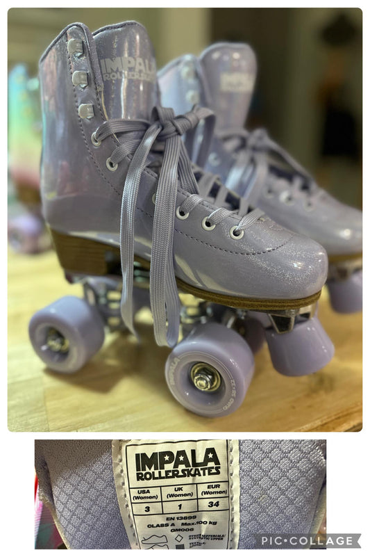 A pair of purple roller skates with white laces and wheels, displayed on a wooden floor. The brand 'IMPALA' is visible on the frame of the skates.