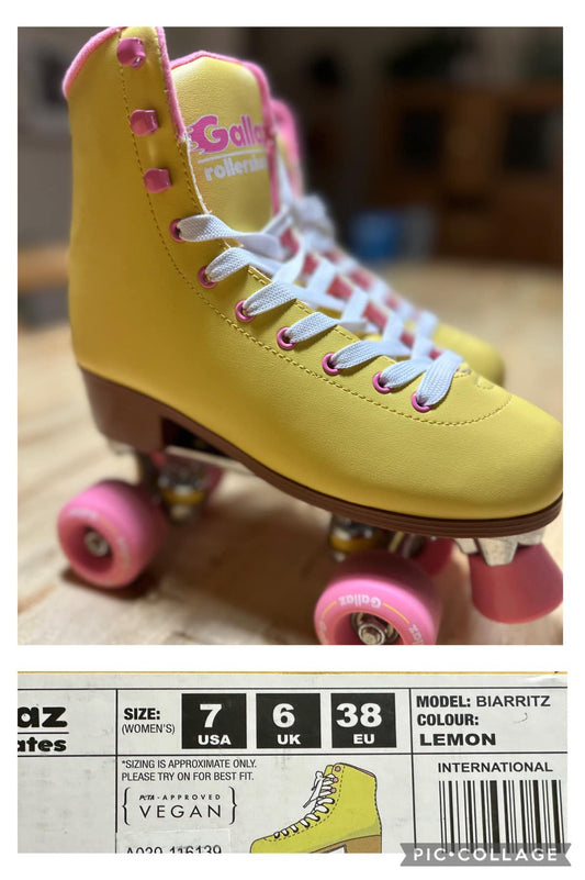 A pair of size US 7 women's yellow roller skates with pink and white details, displayed on a wooden floor.