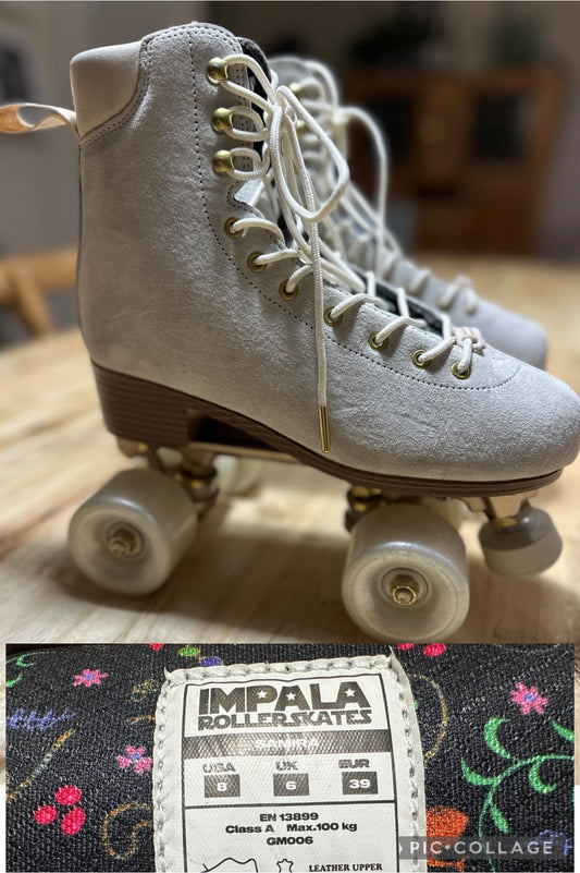 A pair of beige roller skates with white laces and wheels, displayed on a wooden floor. The brand 'IMPALA' is visible on the label.